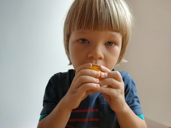 Portrait of boy eating apple against white background