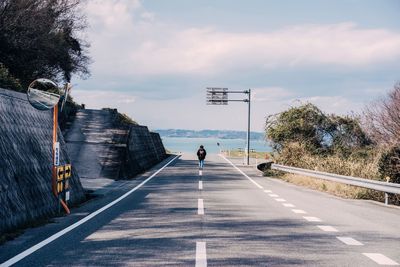 Mid distance of woman walking on road against sky