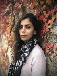 Portrait of beautiful young woman standing against wall