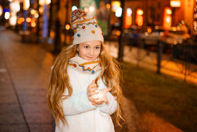 Beautiful girl holding a garland in her hand in the evening on the street