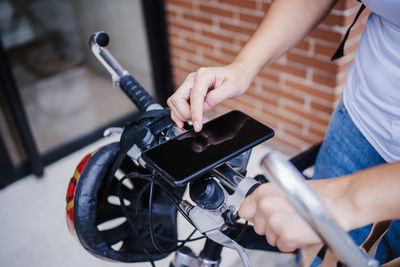 Midsection of woman using mobile phone on bicycle