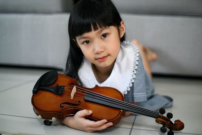 Close-up portrait of girl with violin lying on floor at home