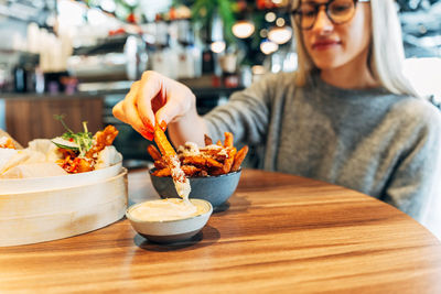 Midsection of woman having food on table