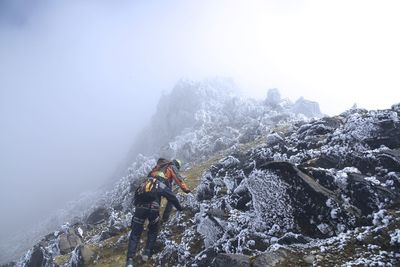 Hikers climbing snowy slope of hill