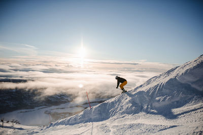 Man skiing on snowcapped mountain against sky