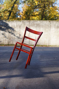 Empty chair on street against trees