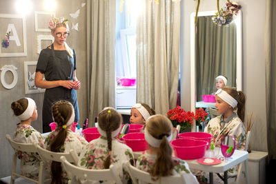 Beautician talking to children at spa during birthday party