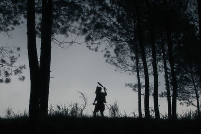 Silhouette woman standing on field against trees in forest