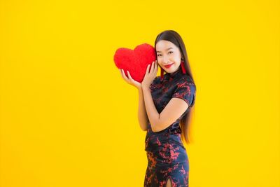 Young woman smiling against yellow background