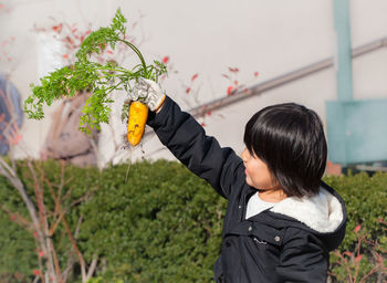 Rear view of woman standing by flowering plants