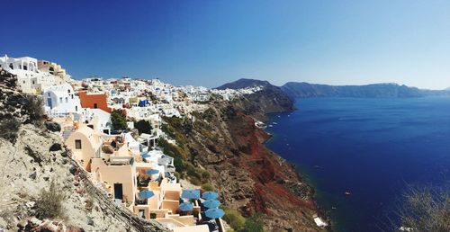 Buildings by sea against clear blue sky