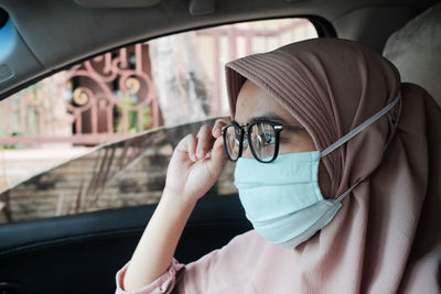 Close-up of woman wearing mask sitting car