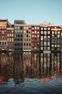 Reflection of building in canal against clear sky