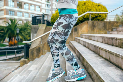 Female runner with palm tree leggings running down stairs in town
