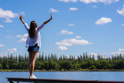 Rear view of young woman standing by lake