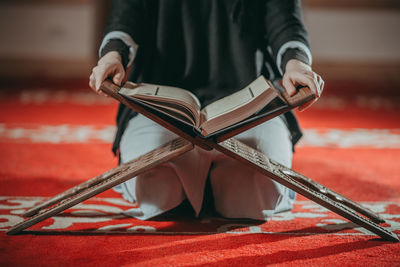 Midsection of woman with koran at mosque