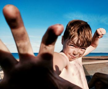 Portrait of shirtless boy on beach against sky