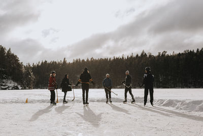 Friends playing hockey on frozen lake