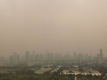 Buildings in city against sky during foggy weather