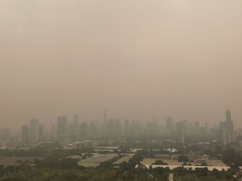 Buildings in city against sky amidst air pollution