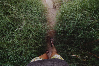 Low section of woman walking on trail amidst grass