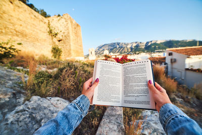 Midsection of woman reading book on paper