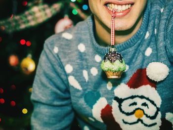 Midsection of man holding christmas decoration in mouth