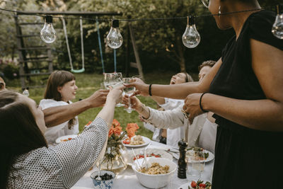 Cheerful female toasting drinks with friends while enjoying during social gathering