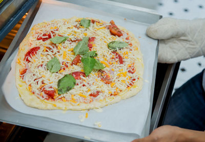 High angle view of hand holding pizza on table