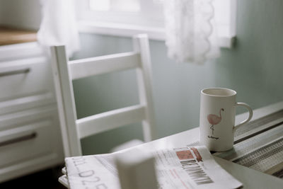 Coffee cup and newspaper on table at home