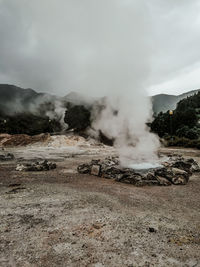 Smoke emitting from volcanic landscape against sky