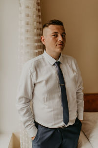 Portrait of young man standing against wall