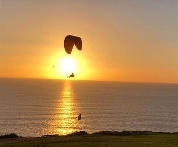 Silhouette people on sea against sky during sunset