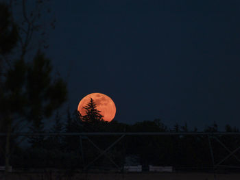 Orange moon against sky at night