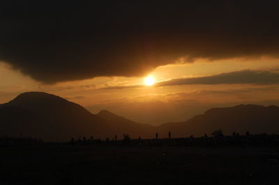 Scenic view of silhouette mountains against orange sky