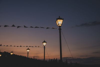 Low angle view of street lights against sky at sunset