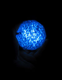 Close-up of hand holding ball against black background