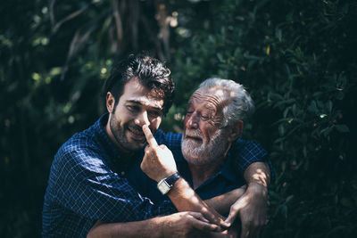 Happy man embracing father while standing by plant