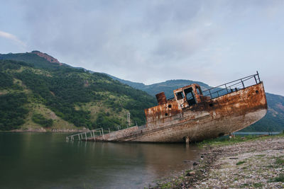 Abandoned boat on river against sky