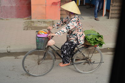 Rear view of people riding bicycle on street