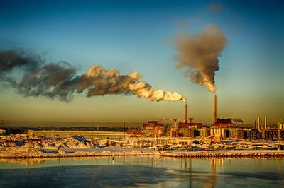 Smoke emitting from factory against clear sky