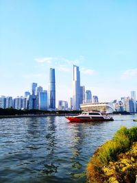 Boats in river by buildings in city against sky