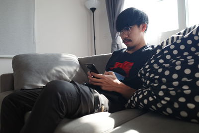 Young woman using laptop while sitting on sofa at home