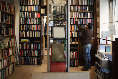 Rear view of man searching book in antique library