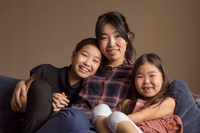 Mom and two daughters on couch at home, smiling woman mother, young girls, moments together