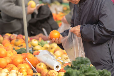 Midsection of man picking fruits at market stall