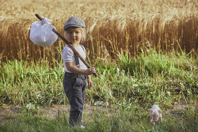 The little traveler met a piglet in the field. retro photo.