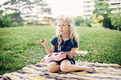 Girl playing pink guitar toy outdoor. child playing music and singing song in park. music hobby 