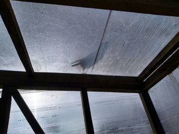 Low angle view of roof against sky seen through window