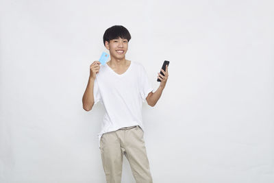 Portrait of smiling young man standing against white background